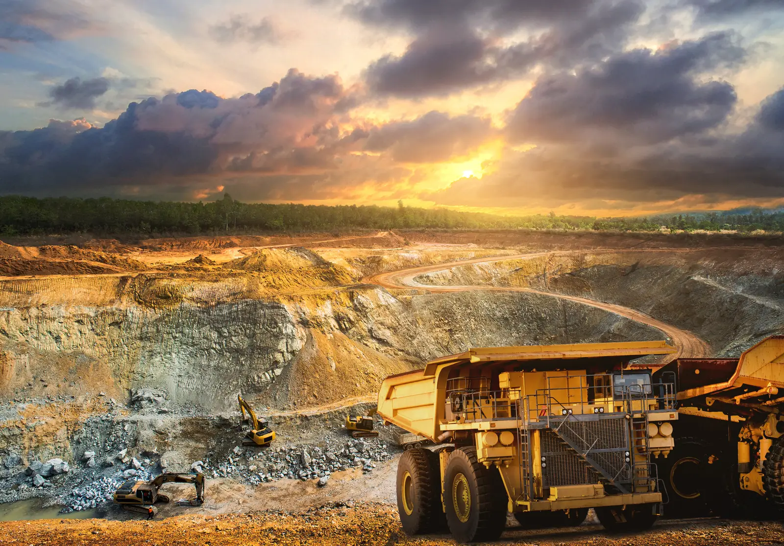 Haul truck working the benches of an open-pit mine at sunset
